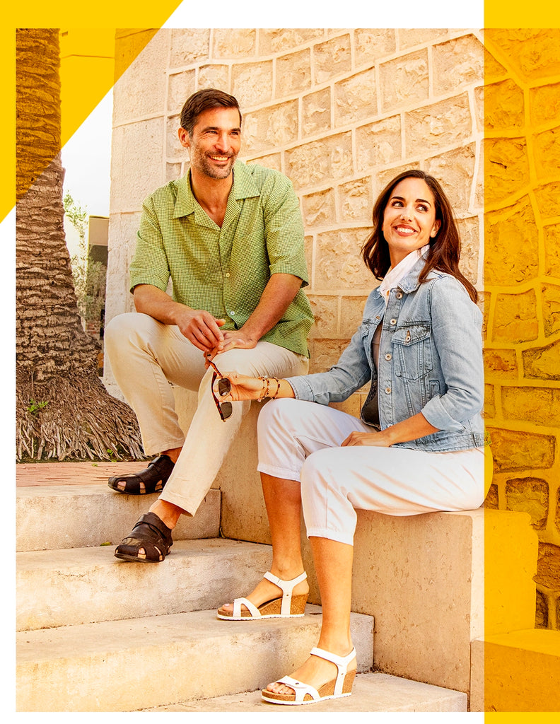 Pareja sentada. Chica con sandalia Julia blanca y chico con sandalia Fletcher marrón